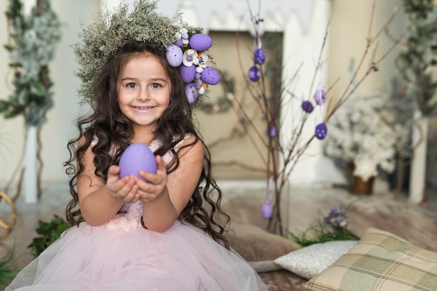 Foto gratuita ragazza felice in corona di fiori con uovo di pasqua