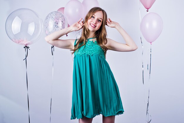 誕生日のテーマを祝う白で隔離の色の風船と緑のターコイズドレスで幸せな女の子