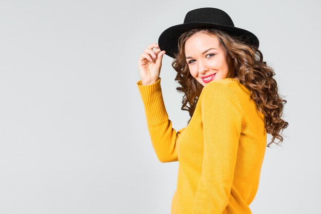 The happy girl in hat on gray studio wall