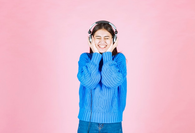 happy girl in headphones standing on pink.