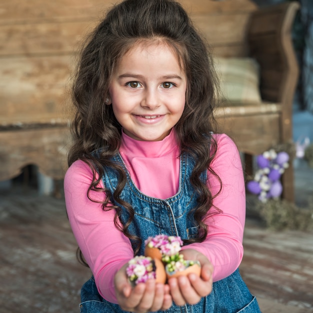 Happy girl holding broken eggs with flowers 