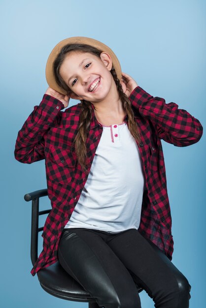 Happy girl holding hat on head 