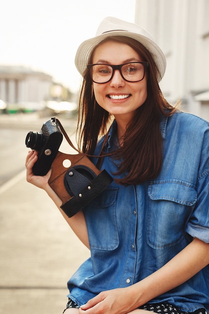 Foto gratuita ragazza felice che tiene macchina fotografica e sorridente