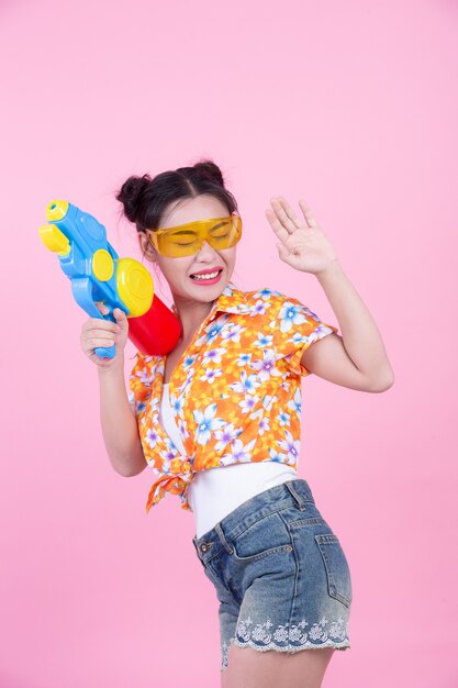 Happy girl holding a pink background water gun.