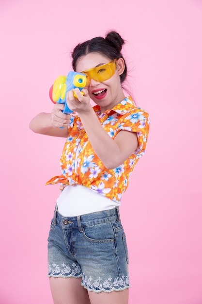 Happy girl holding a pink background water gun.