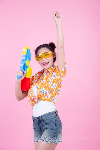 Счастливая девушка держа розовый водяной пистолет предпосылки.