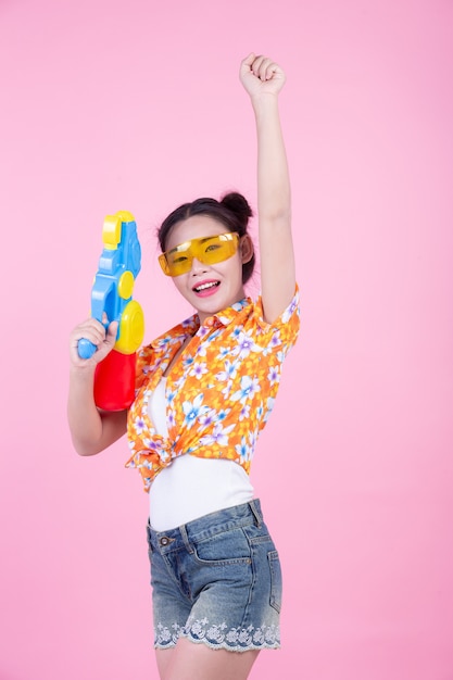 Happy girl holding a pink background water gun.