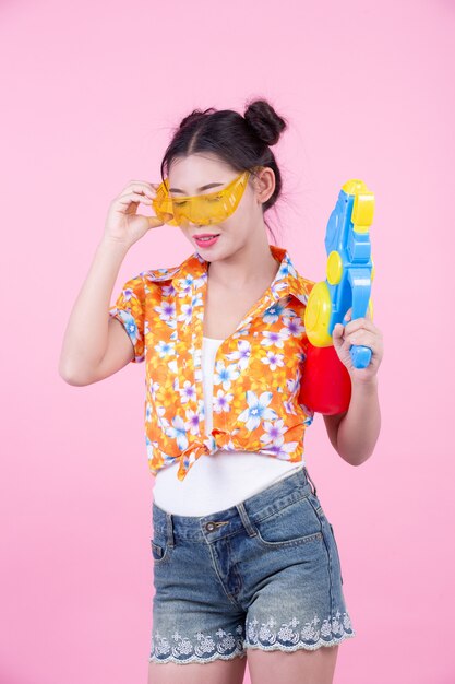 Happy girl holding a pink background water gun.