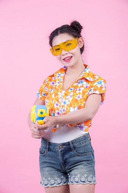 Happy girl holding a pink background water gun.