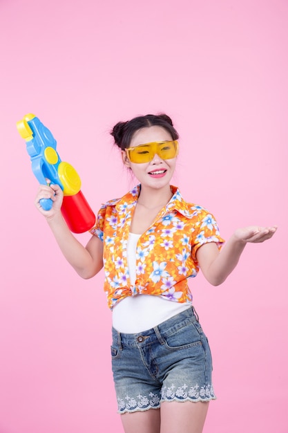 Happy girl holding a pink background water gun.