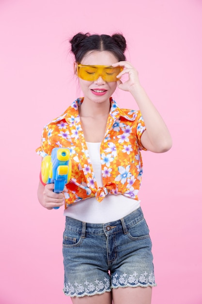 Happy girl holding a pink background water gun.