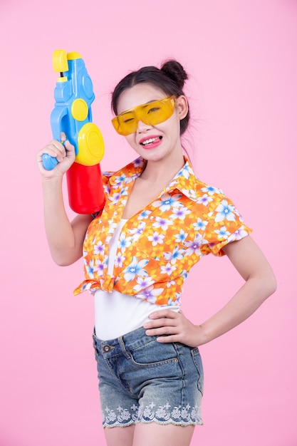 Happy girl holding a pink background water gun.