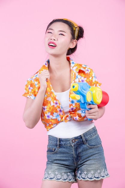 Happy girl holding a pink background water gun.