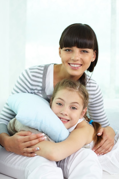 Happy girl hugging a cushion with his mother