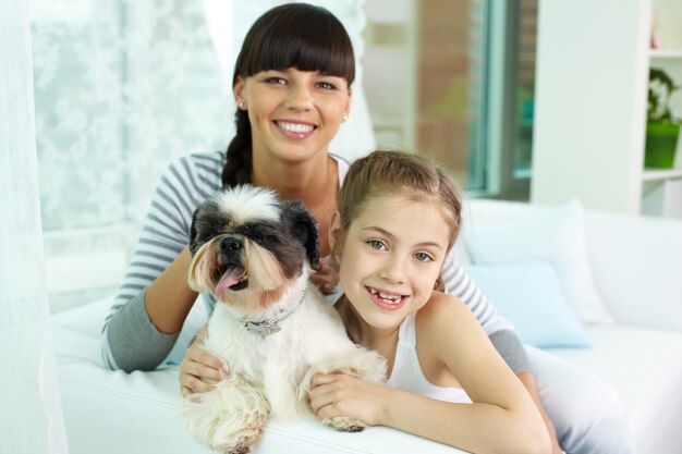 Happy girl hugging the dog with her mother