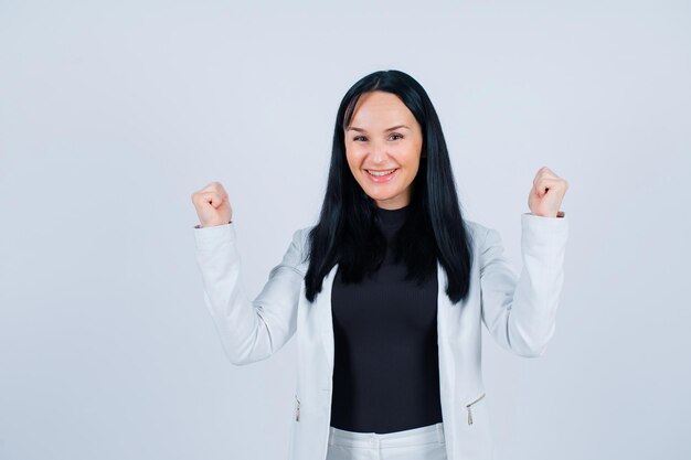 Happy girl is raising up her fists on white background