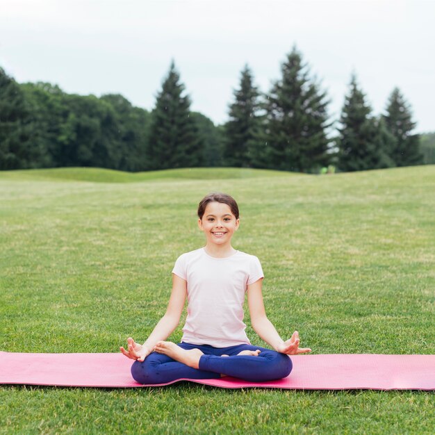 Happy girl in lotus position relaxing in nature