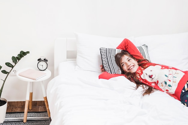 Happy girl lying on cozy white bed