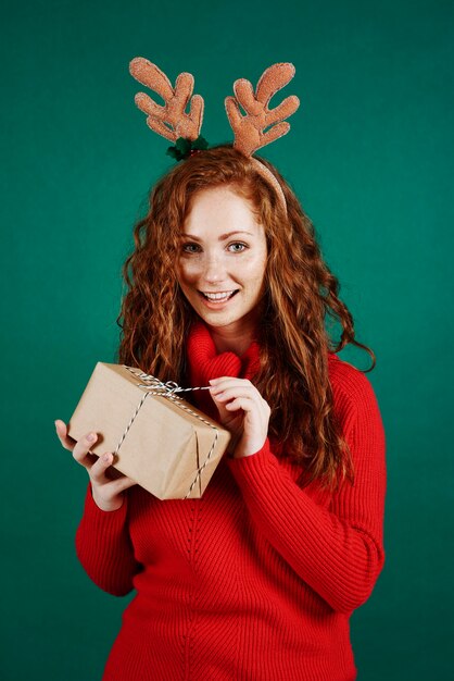 Счастливая девушка, открывающая рождественский подарок в студии