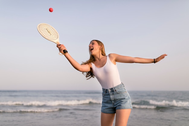 Счастливая девушка играет в теннис возле побережья