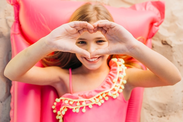 Foto gratuita ragazza felice che riposa sulla stuoia dell'aria di colore durante le vacanze estive