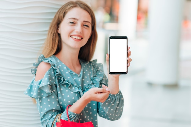 Foto gratuita ragazza felice che mostra il suo telefono