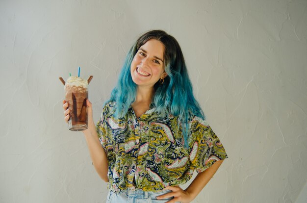 Happy girl smiling with a big chocolate milkshake in a coffee shop