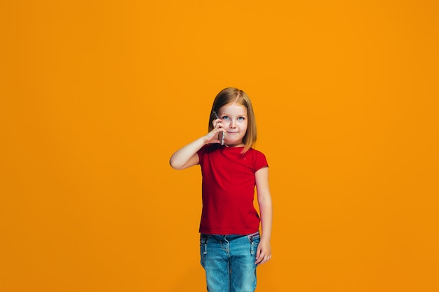 The happy girl standing and smiling against orange wall