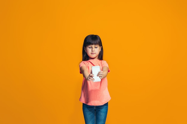 Free photo the happy girl standing and smiling against orange wall