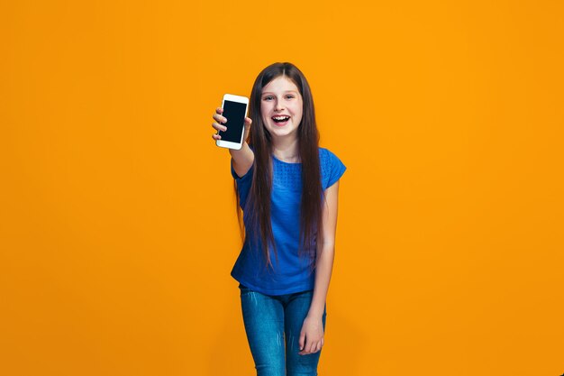 The happy girl standing and smiling against orange wall