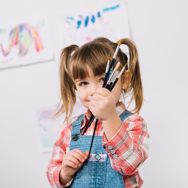 Happy girl standing with paint brushes in hands