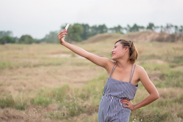 Happy girl taking a photo in the meadow