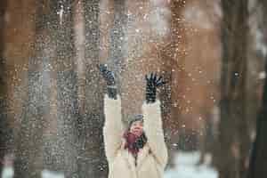 Foto gratuita la ragazza felice gettando neve