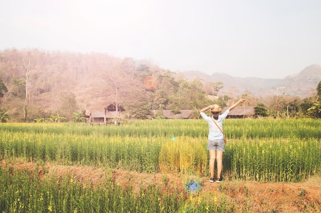 Happy girl traveler standing in flowers field, Summer vacation