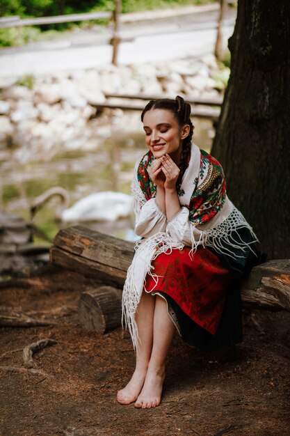 Happy girl in a Ukrainian embroidered dress sitting on the bench