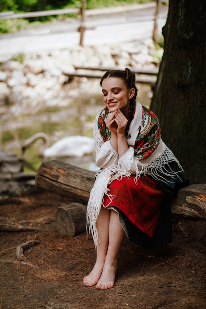 ベンチに座ってウクライナ刺繍ドレスで幸せな女の子
