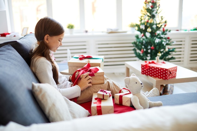 Счастливая девушка разворачивает рождественские подарки