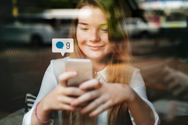 Happy girl using social media on smartphone in a cafe