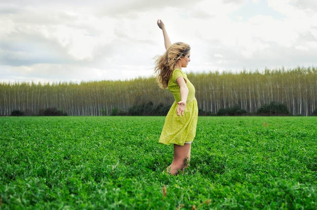 Happy girl with arms up in the meadow