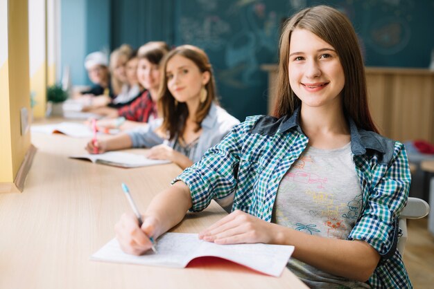 Happy girl with classmates at table