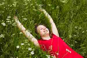 Foto gratuita ragazza felice con gli occhi chiusi che si trovano sull'erba in bella natura