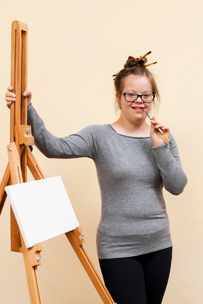 happy girl with down syndrome posing next to easel