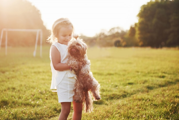 Ragazza felice con il suo cane nel parco al tramonto