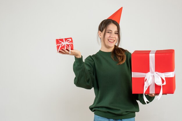 happy girl with party cap holding her christmas gifts on white