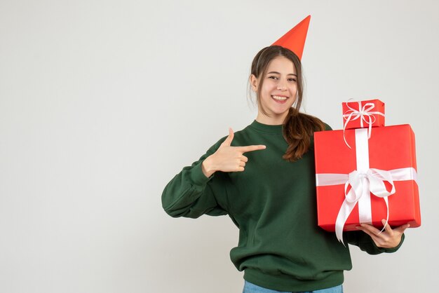 화이트에 그녀의 크리스마스 선물을 가리키는 파티 모자와 함께 행복 한 소녀