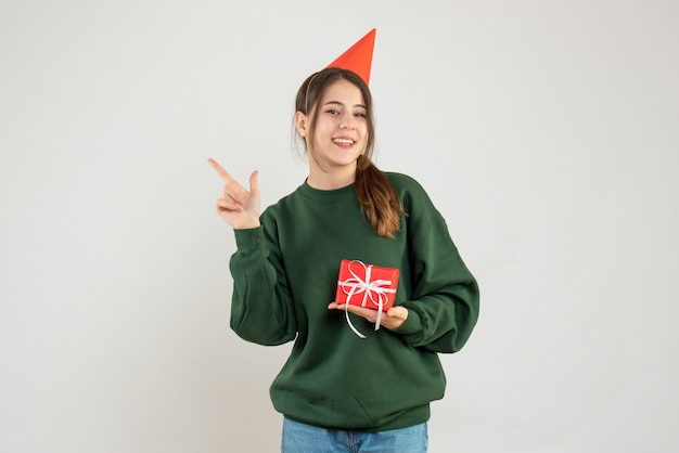 happy girl with party cap pointing at something on white