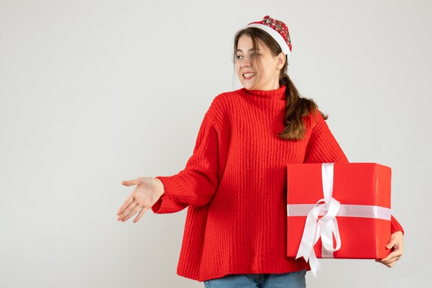 happy girl with santa hat giving hand holding gift on white
