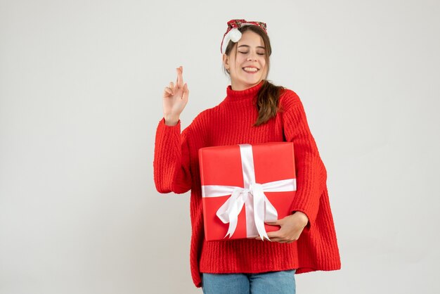 happy girl with santa hat holding gift making good luck sign on white