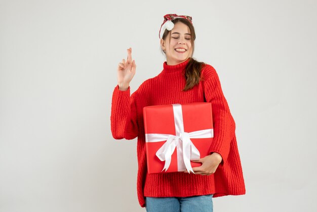 화이트에 행운을 빌어 요 기호를 만드는 선물을 들고 산타 모자와 함께 행복 한 소녀