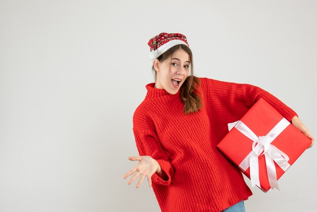 happy girl with santa hat holding gift standing on white